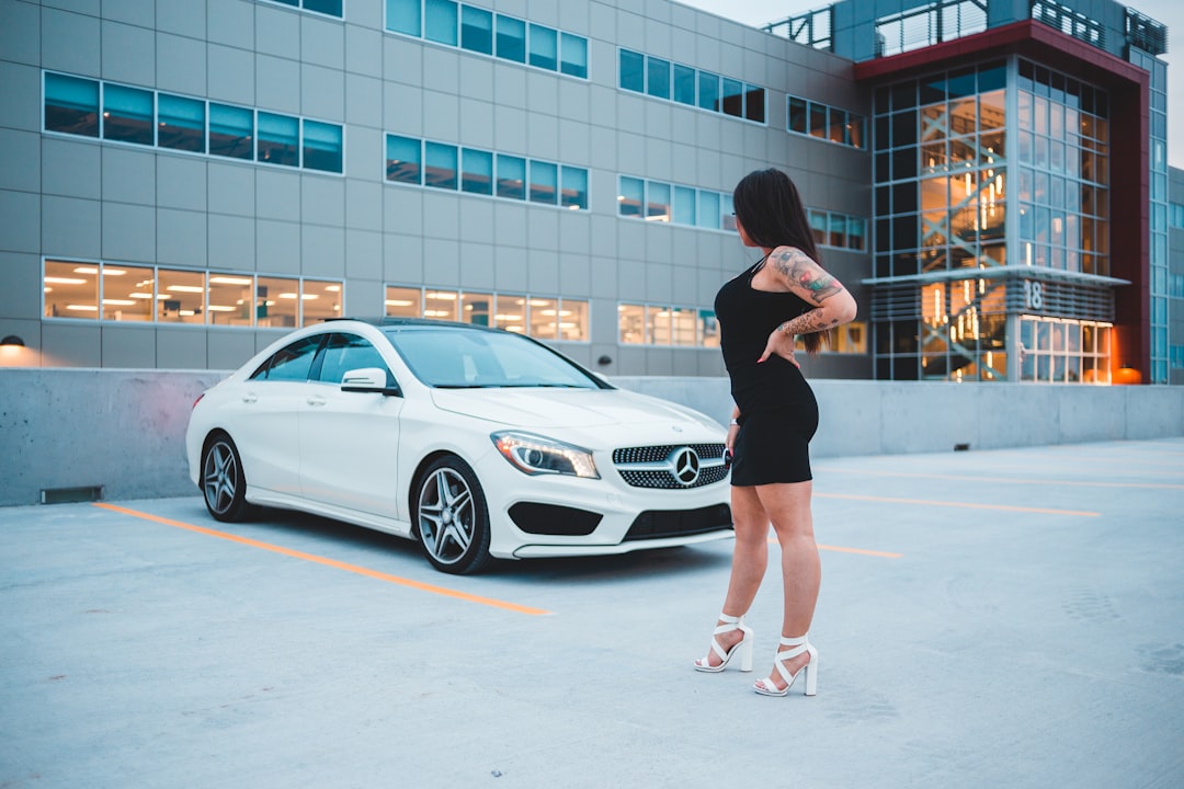 woman in black mini dress standing beside white mercedes benz coupe