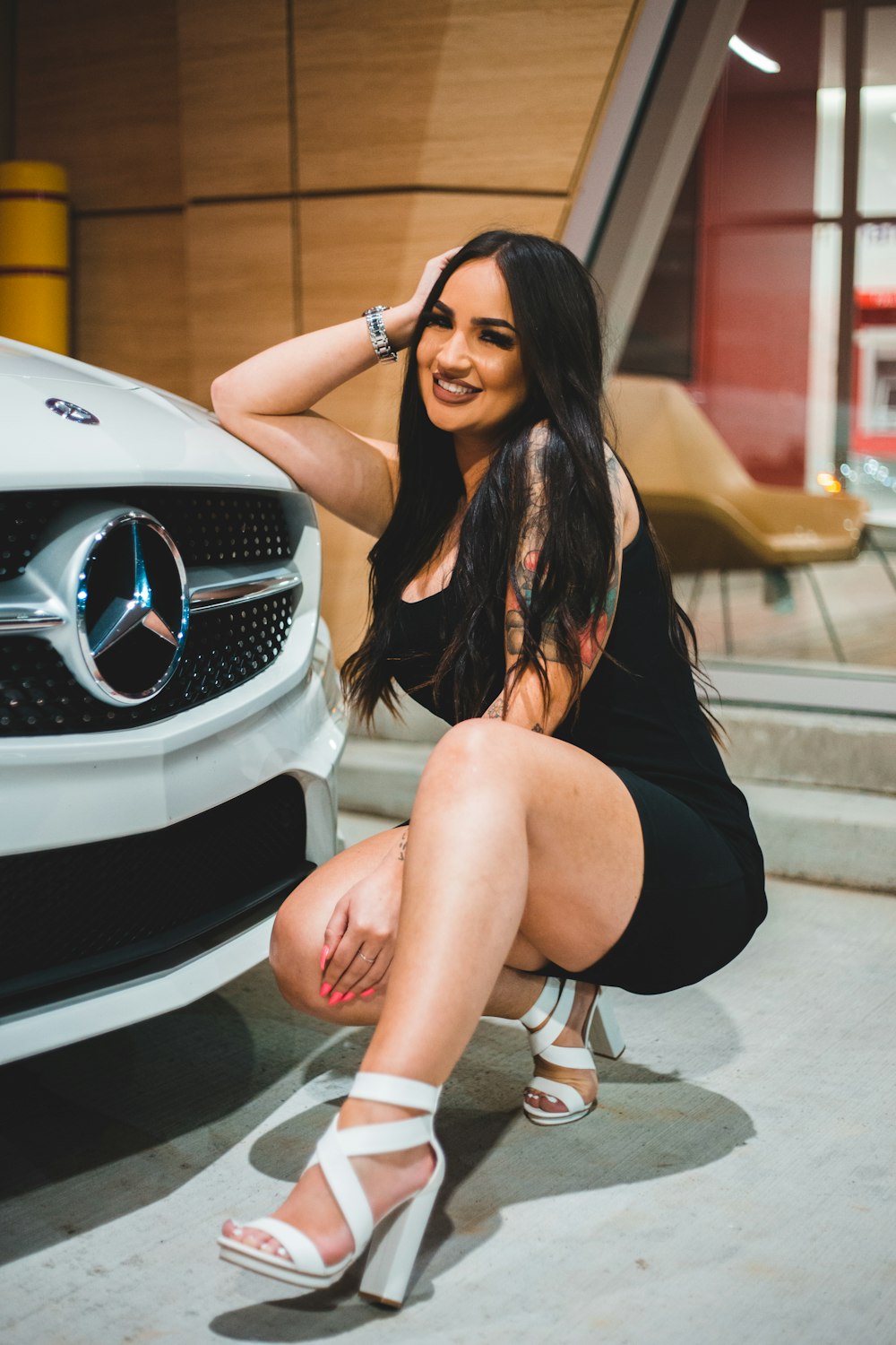 woman in black sleeveless dress sitting on white car