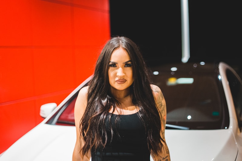 woman in black tank top standing beside white car