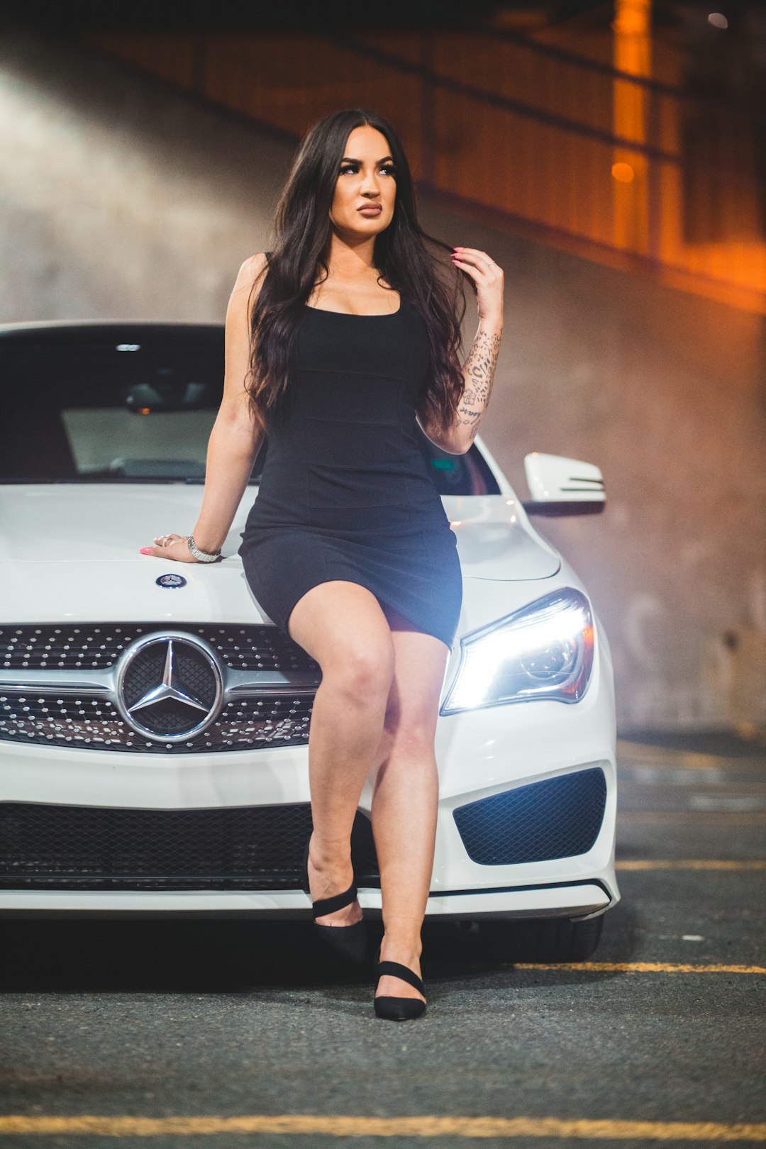 woman in black tank top and blue denim shorts sitting on white mercedes benz car