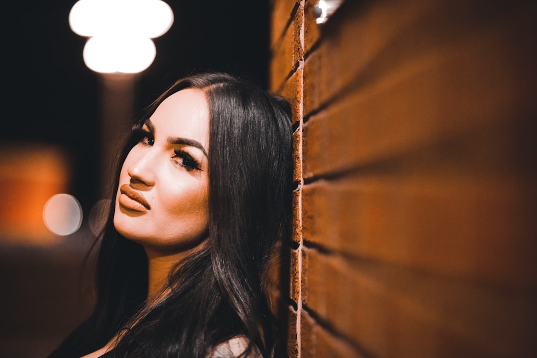 woman in black shirt standing near brown wooden wall