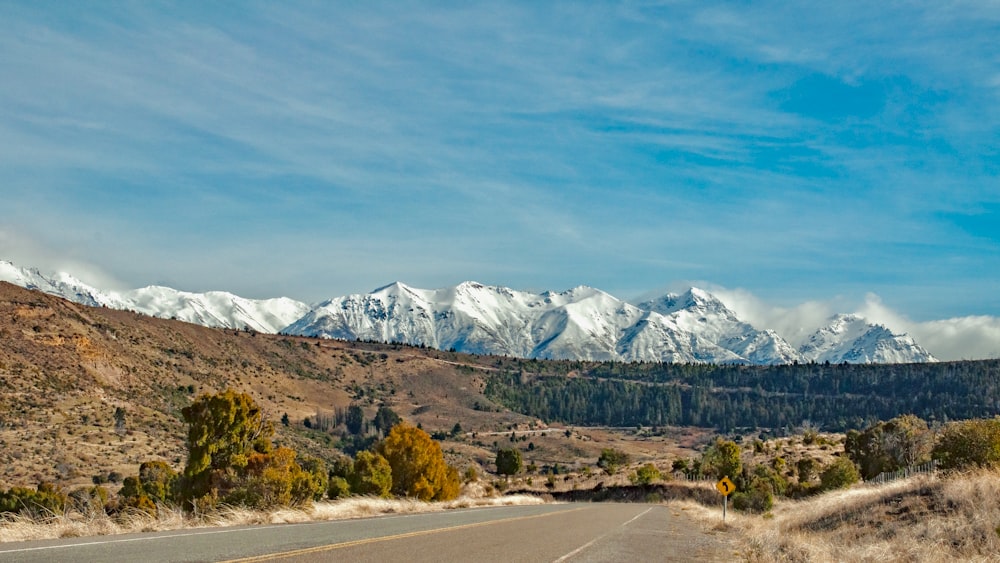 gray concrete road near mountain under blue sky during daytime