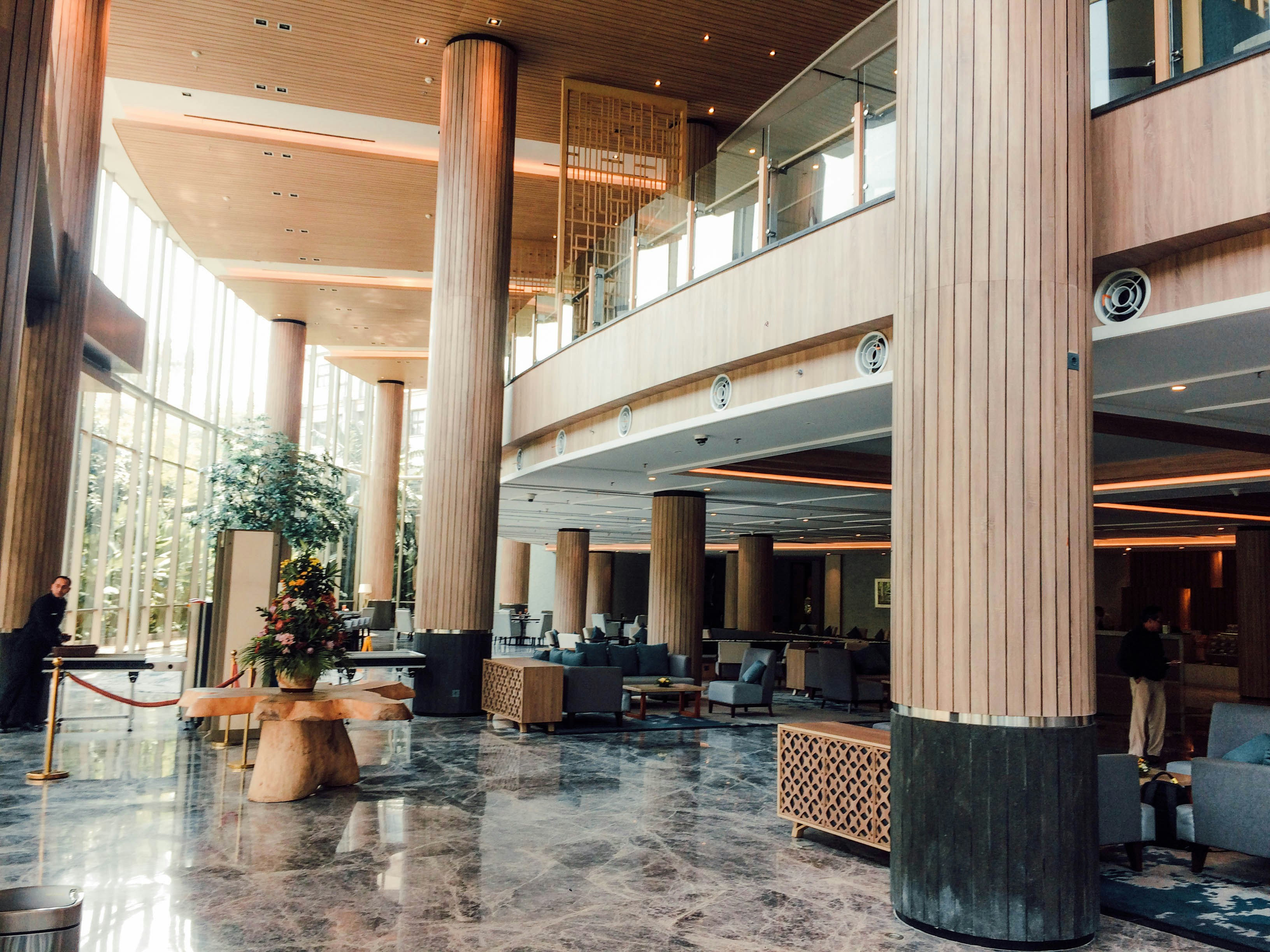 Expansive luxury hotel lobby with marble floors, custom wood reception desk, and dramatic lighting installation