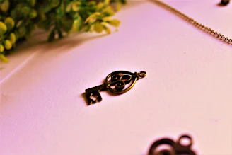 Close-up of a delicate 3D printed charm shaped like a tiny vintage key with intricate details.