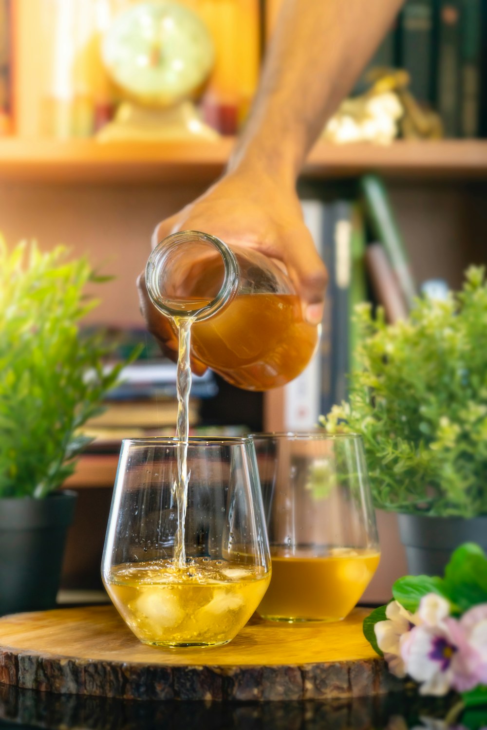 person pouring orange juice on clear drinking glass