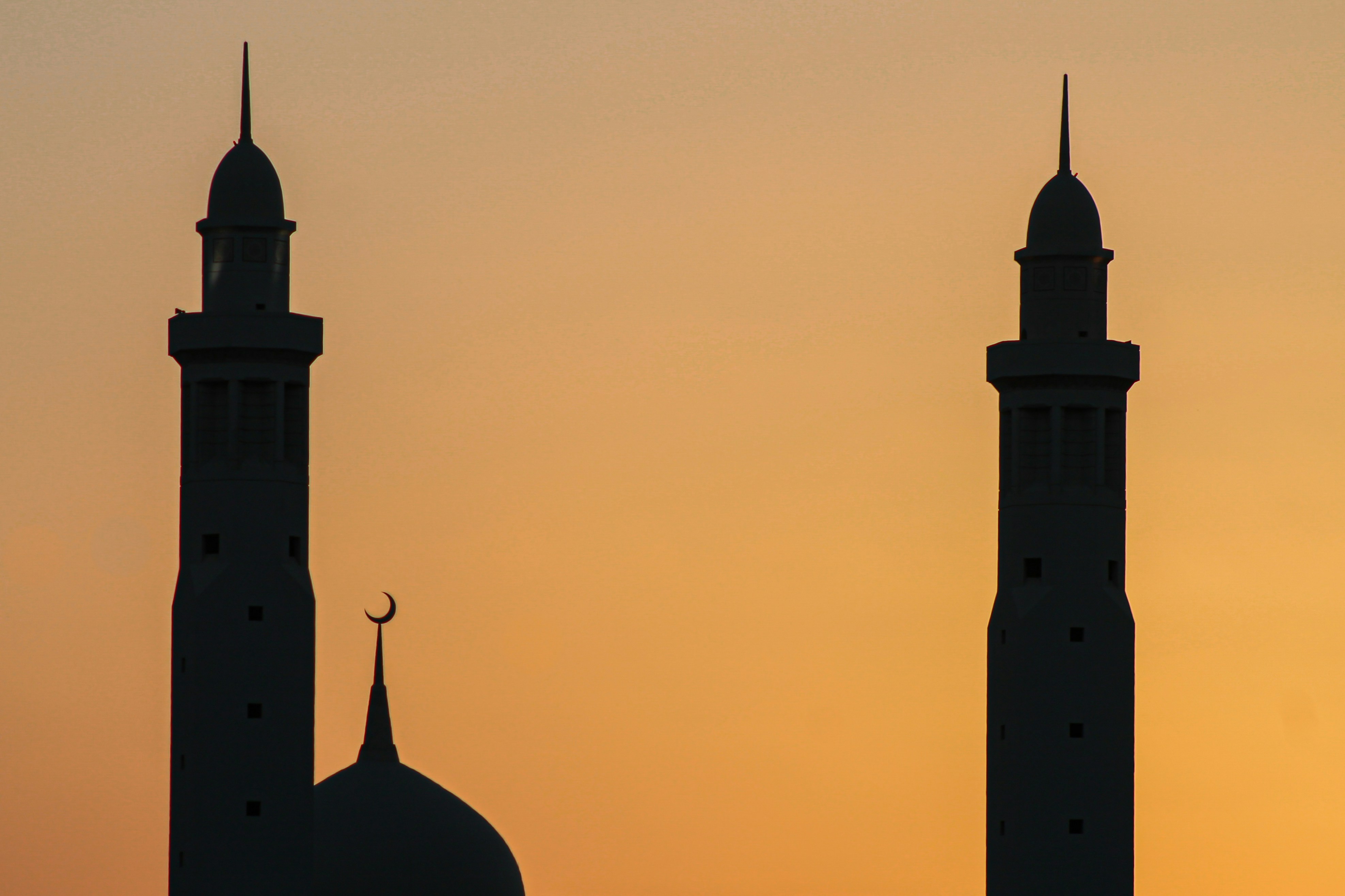 A silhouette of mosque minarets against a sunset