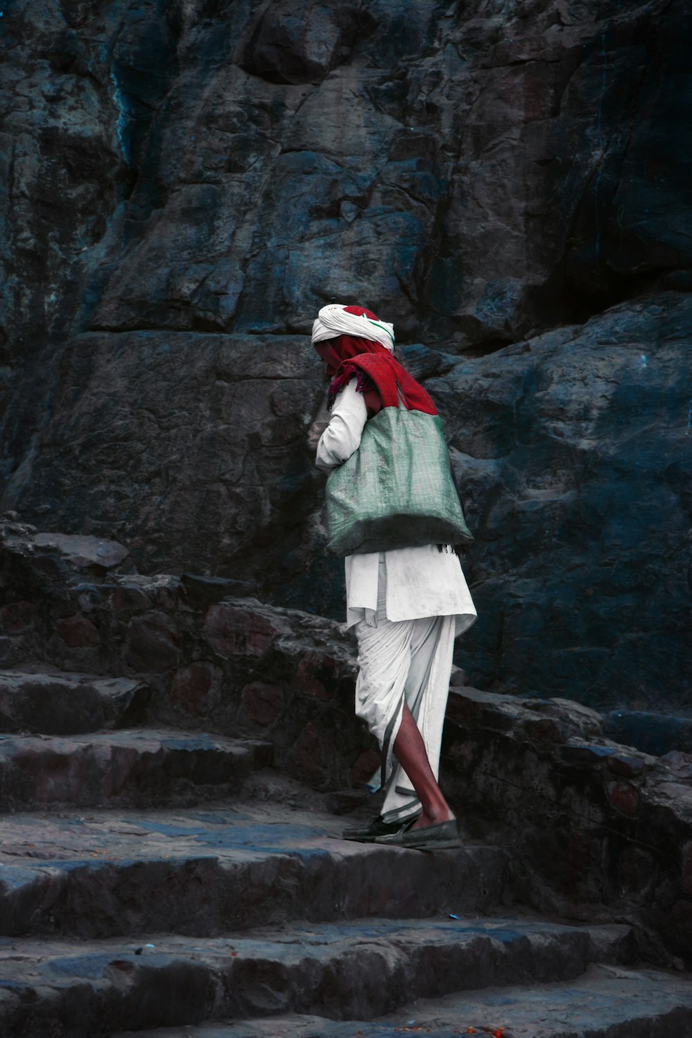 woman in green jacket and white pants standing on rocky ground