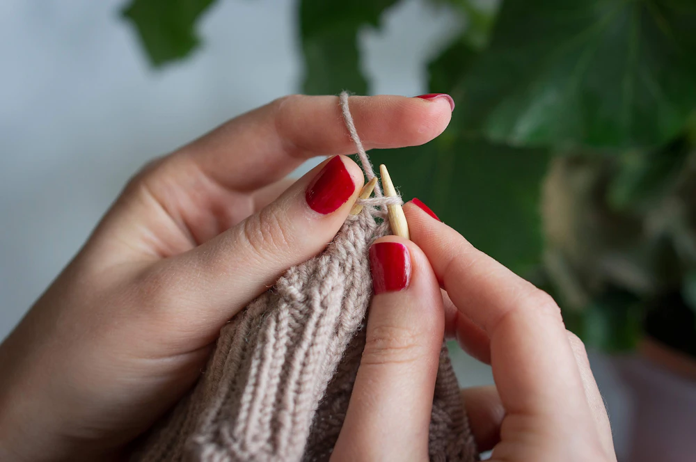 Hands knitting a textured piece of fabric