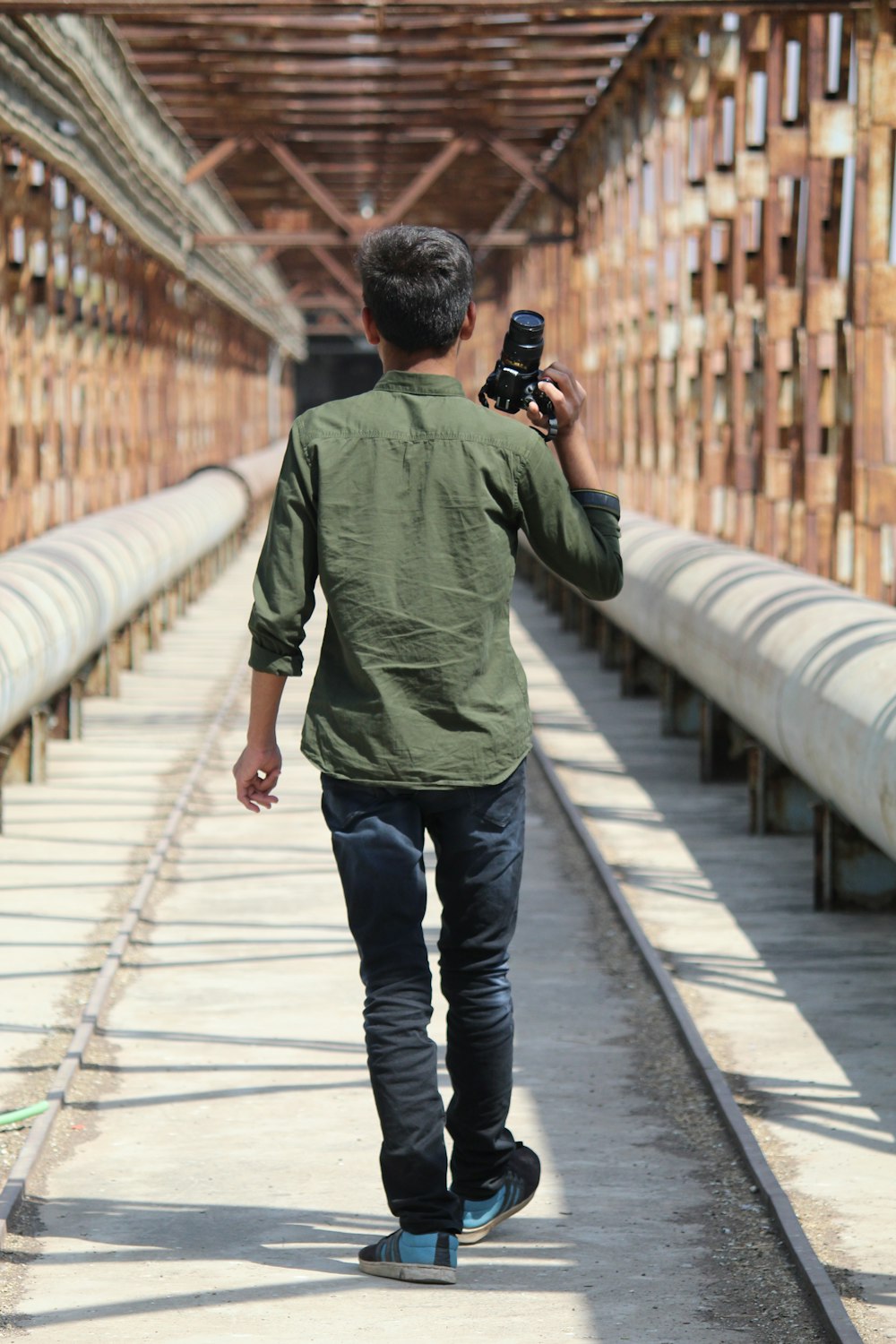 man in green shirt and black pants walking on bridge