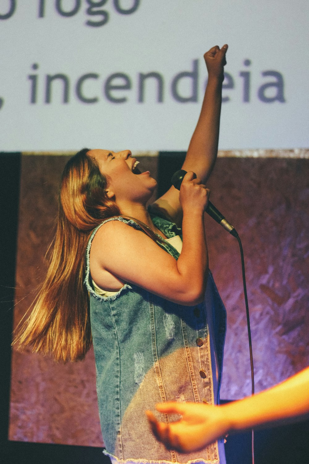 woman in blue denim vest singing