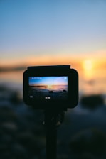 black dslr camera taking photo of sunset