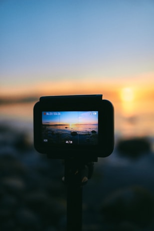 black dslr camera taking photo of sunset
