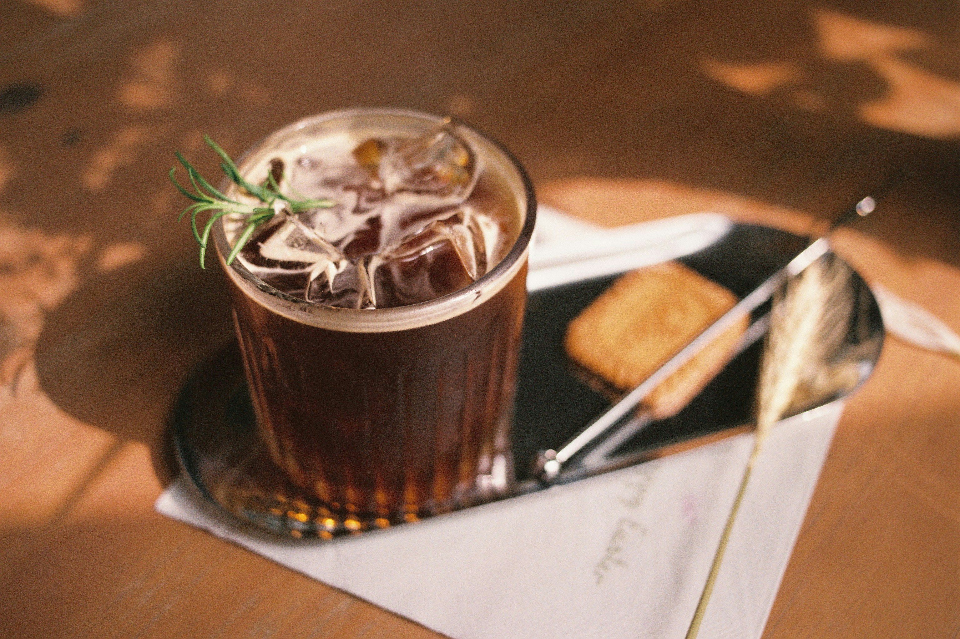 Iced coffee in a glass with a sprig of rosemary
