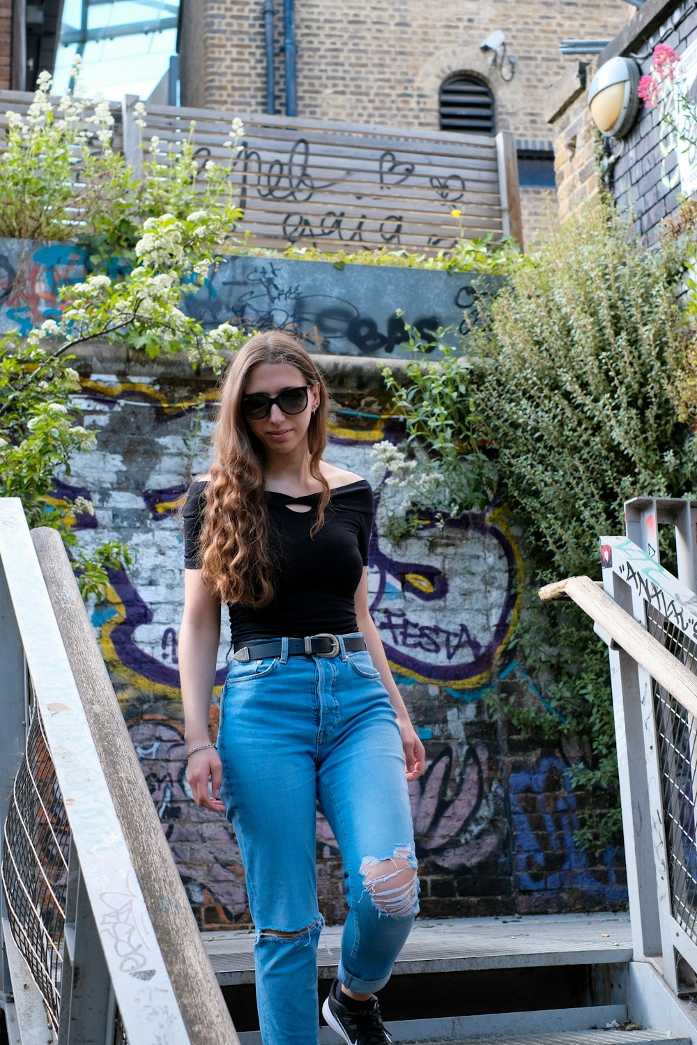 Woman in black tank top and blue denim jeans sitting on brown wooden bench  during daytime photo – Free Jeans Image on Unsplash