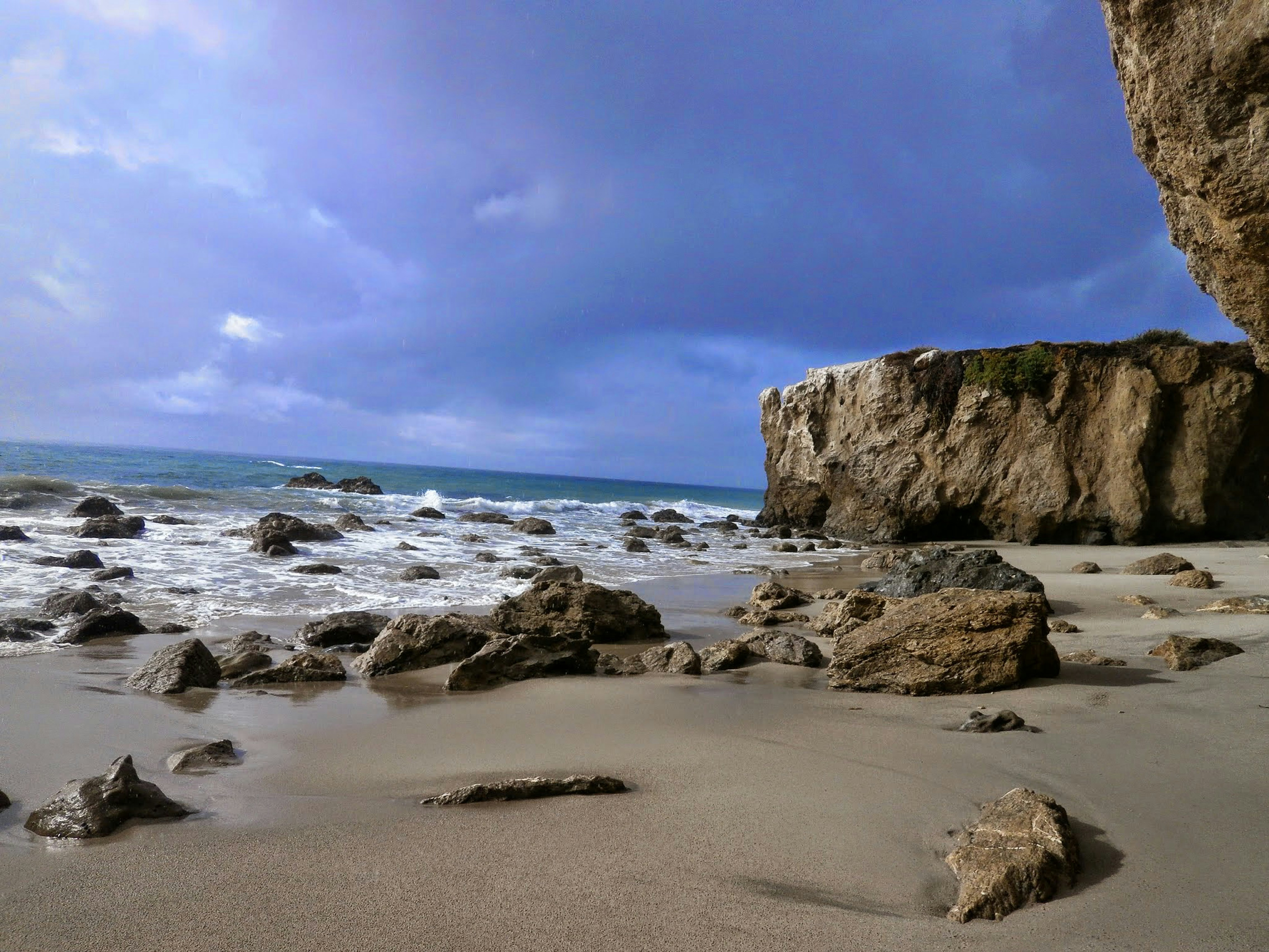 brown rock formation on sea shore under white clouds and blue sky during daytime
