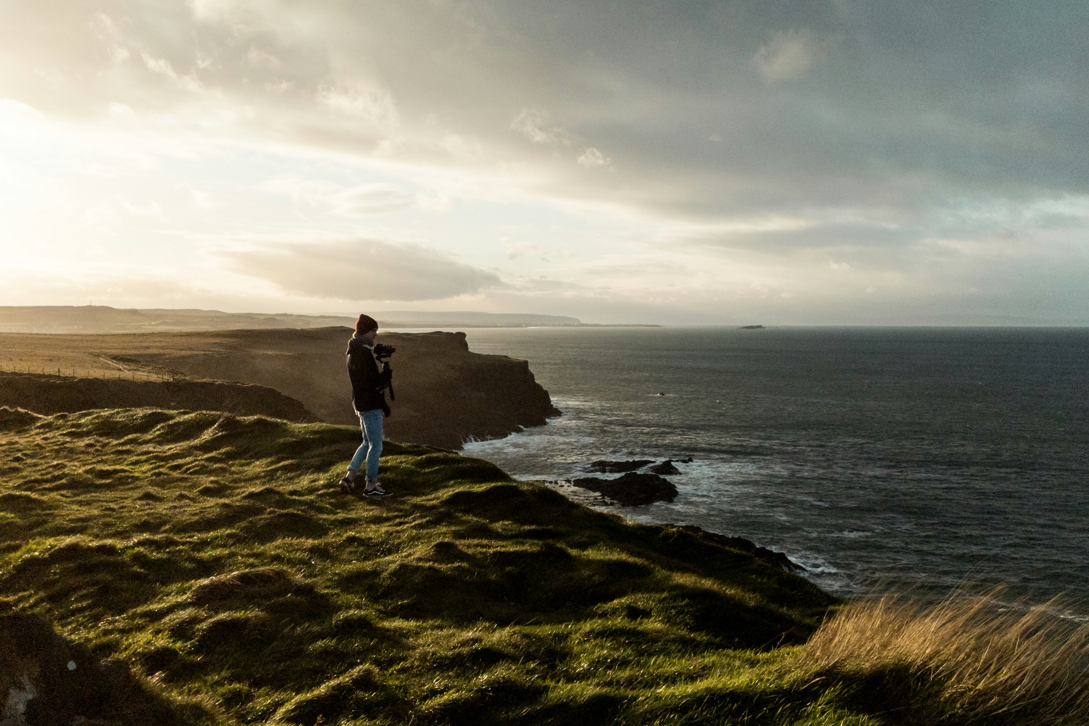 man in black shirt and blue denim jeans standing on cliff during daytime