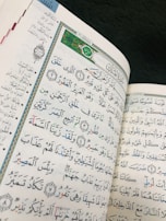 A close-up of an open Quran with delicate floral decorations on the margins.