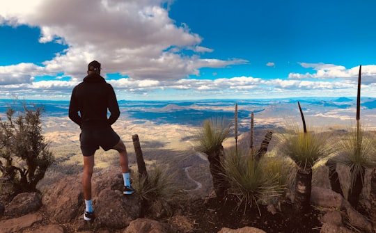 man in black jacket and black shorts standing on brown rock near sea during daytime in Main Range National Park Australia