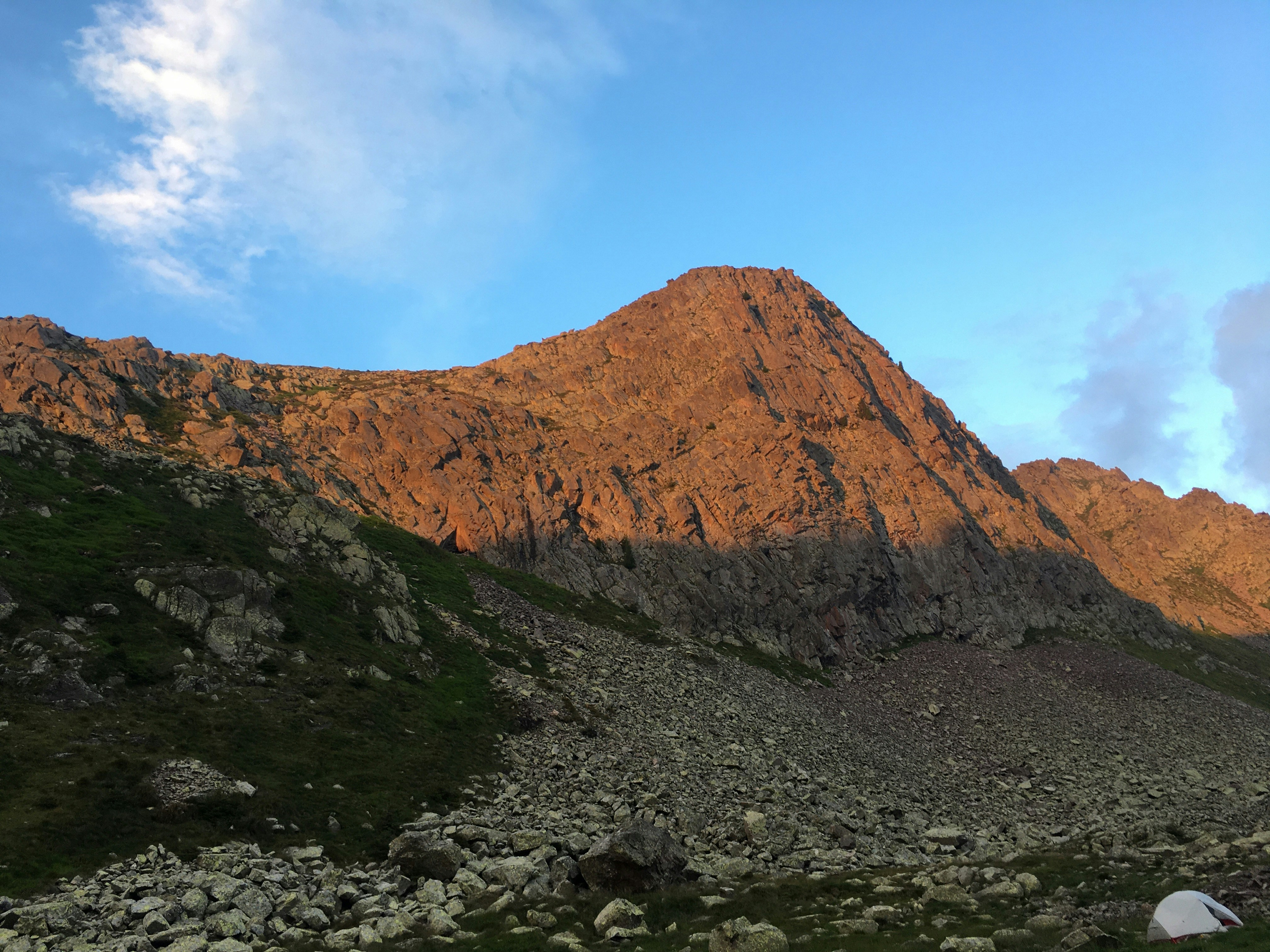 a rocky mountain with a tent in the foreground