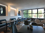 Minimalist café interior with black matte walls, golden accents, and soft emerald lighting.