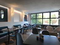 Modern café interior with black matte walls, golden accents, and emerald green lighting