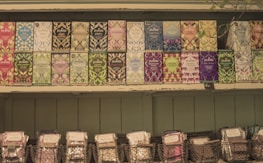 A selection of Pukka tea boxes arranged neatly on wooden shelves. Each box features vibrant and diverse artwork, showcasing various flavors such as peppermint, night time, and elderberry. Below the tea boxes, wire baskets hold additional packaged products.