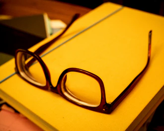 A stack of criminology books with a pair of glasses resting on top.