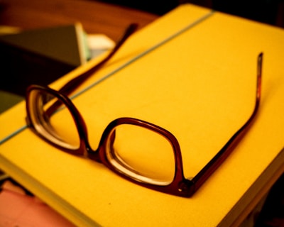 A stack of personal finance books with a pair of glasses resting on top.