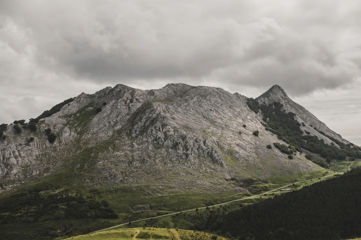 Grey limestone peaks above green slopes in the Urkiola Natural Park, another Basque range, under heavy cloud