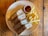 A plate of sandwiches with a creamy filling is served alongside a portion of golden French fries and a small cup of dipping sauce. The plate is placed on a rustic wooden table, adding a warm and inviting touch to the presentation.