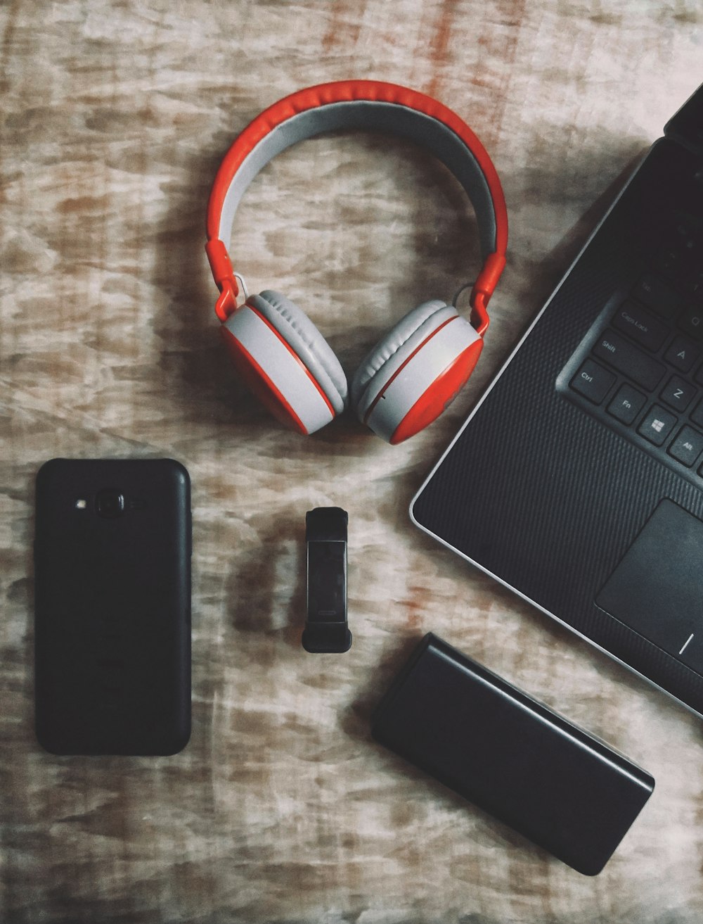 black iphone 5 beside red and white headphones