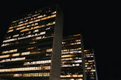 Urban business district at dusk with illuminated office windows symbolizing activity.