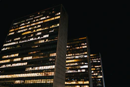 Urban business district at dusk with illuminated office windows symbolizing activity.