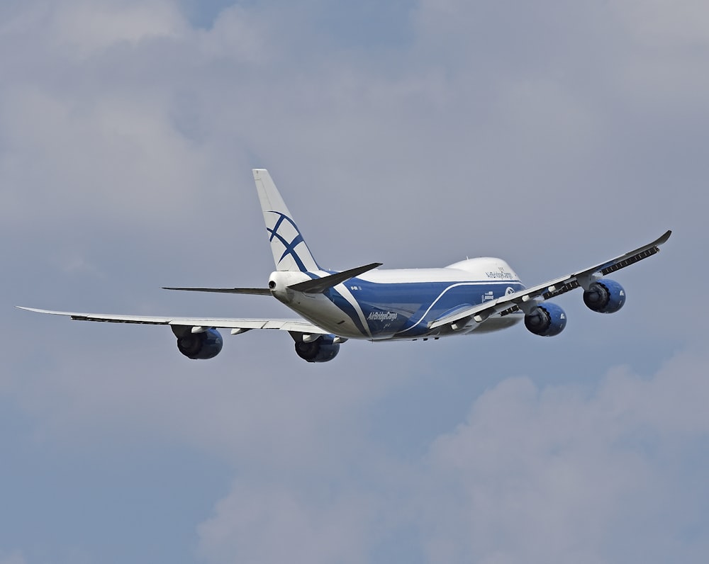 blue and white airplane in mid air during daytime