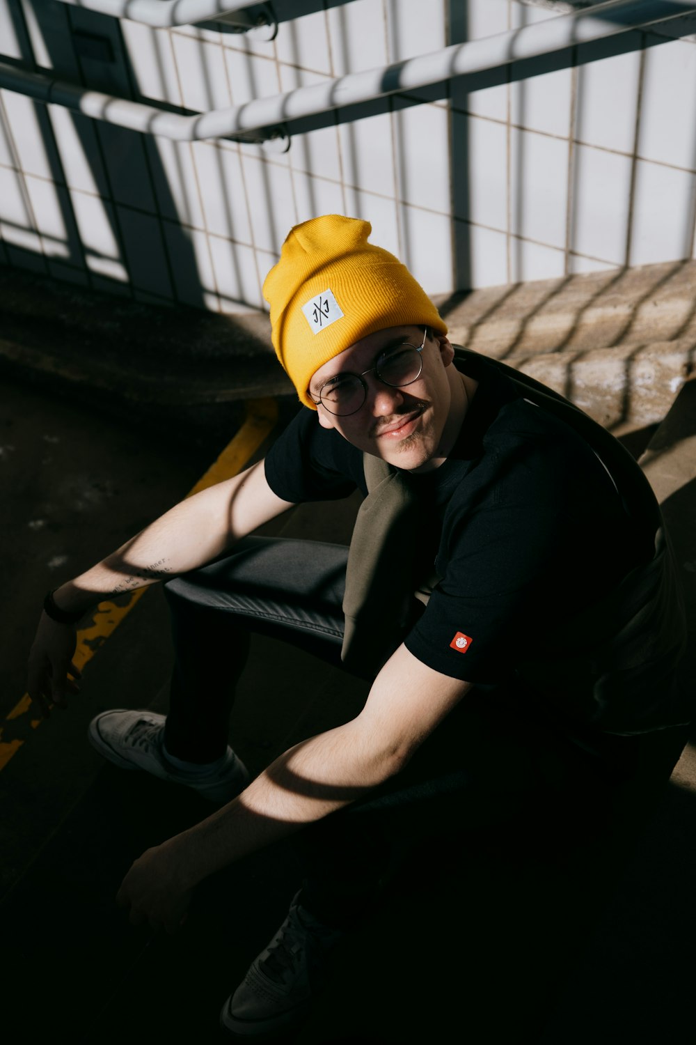 man in black tank top and yellow knit cap sitting on black metal bench