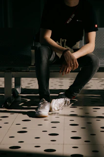 Casual scene of a man sitting on a bench wearing relaxed-fit trousers and sneakers.