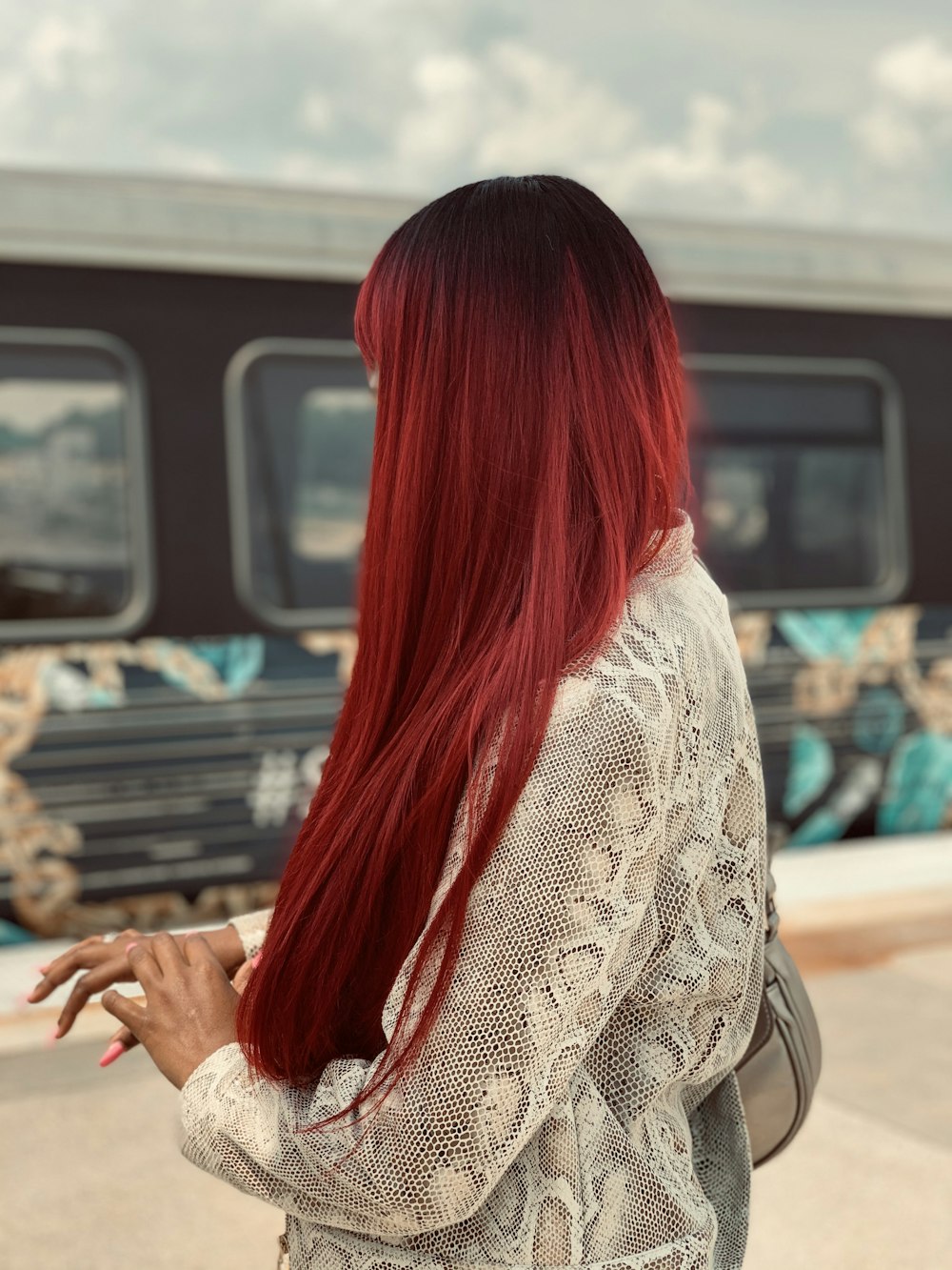 a woman with red hair standing in front of a train