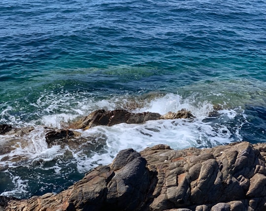 ocean waves crashing on brown rocky shore during daytime in Hyères France