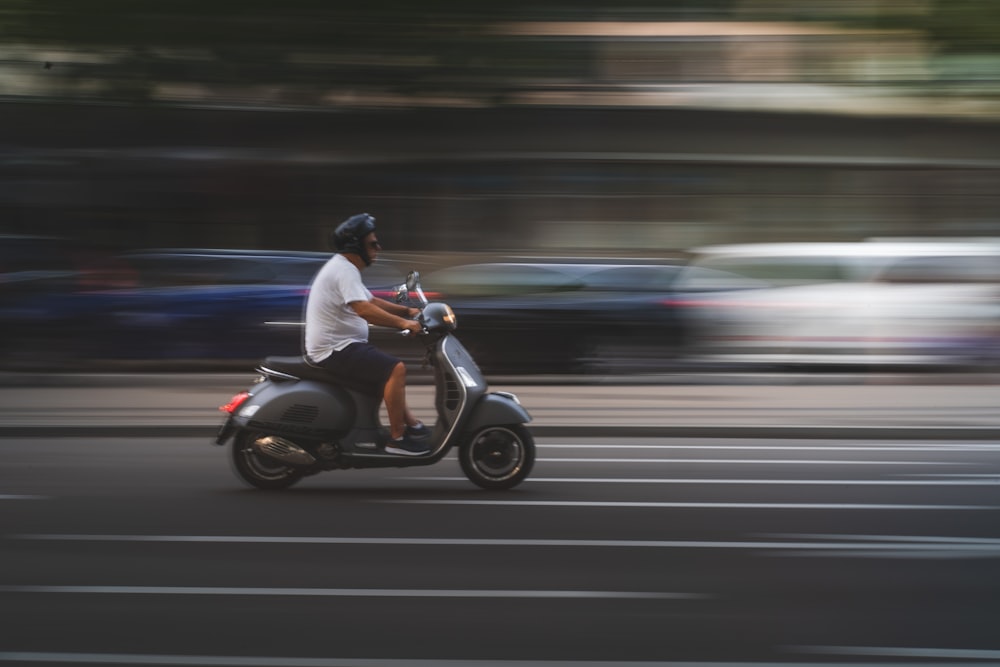 man in white shirt and black pants riding on black motor scooter