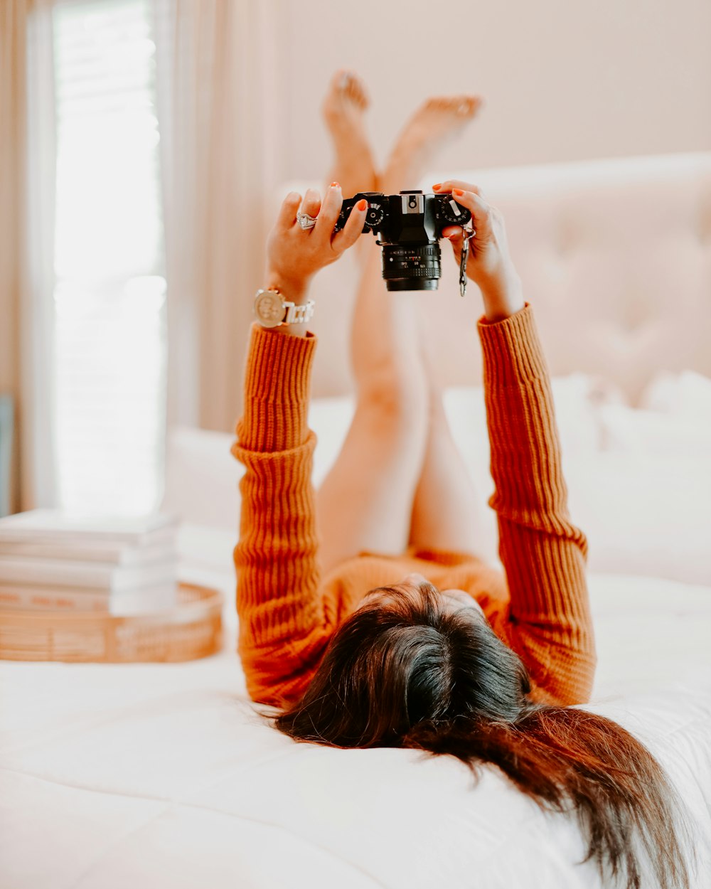 woman in orange long sleeve shirt holding black dslr camera