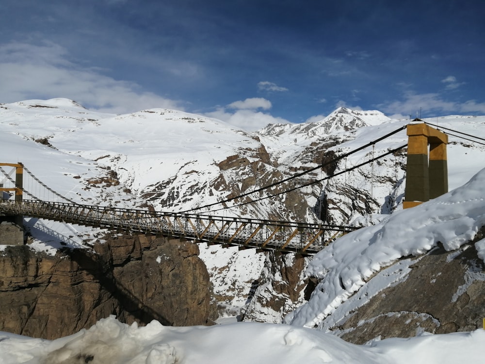 brown wooden bridge over snow covered ground under blue sky during daytime