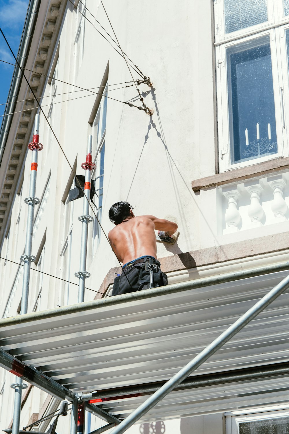 man in black shorts sitting on white metal bar during daytime