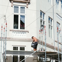 man in black t-shirt and black shorts sitting on black metal railings during daytime