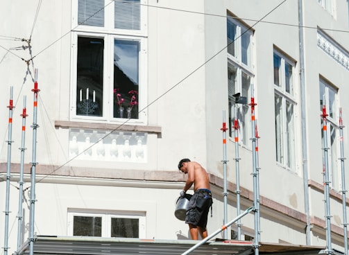 man in black t-shirt and black shorts sitting on black metal railings during daytime