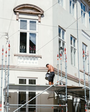 man in black t-shirt and black shorts sitting on black metal railings during daytime