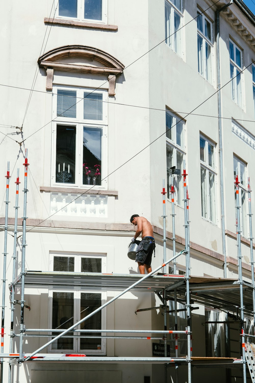 Hombre con camiseta negra y pantalones cortos negros sentado en barandillas de metal negro durante el día