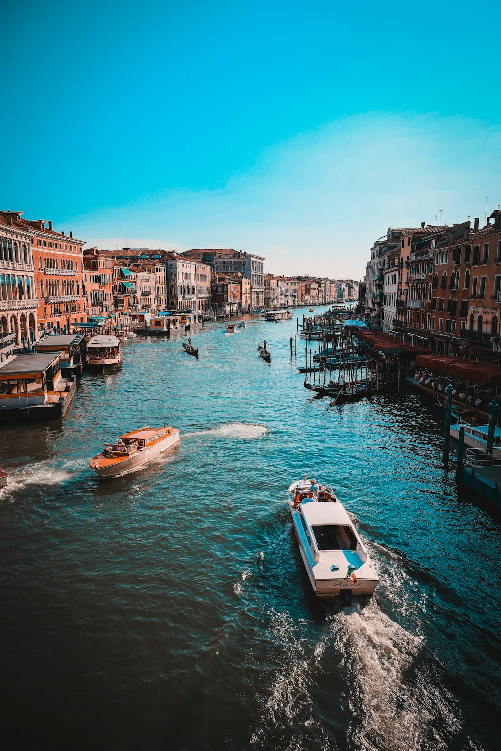 white and brown boat on river between buildings during daytime