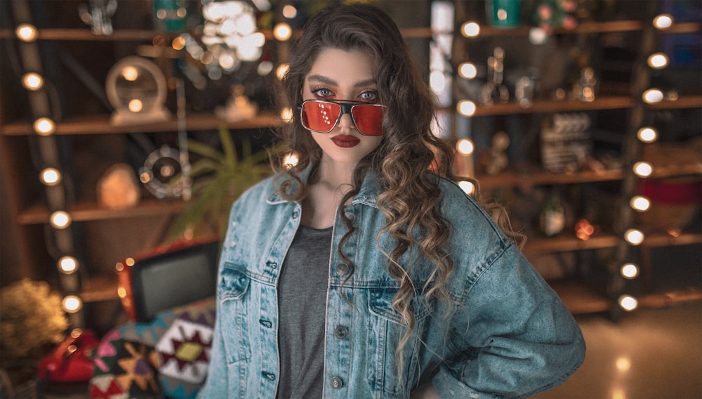 woman in blue denim jacket wearing red sunglasses