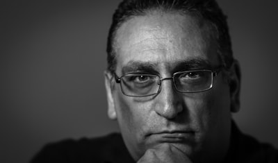 man wearing black framed eyeglasses head zoom background