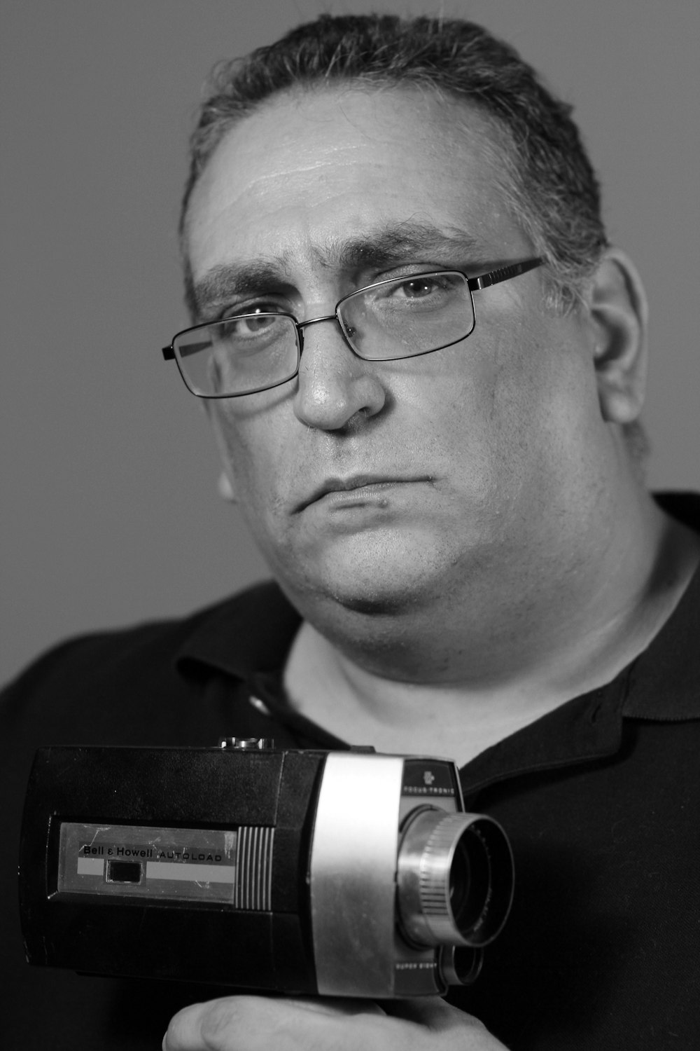 hombre con gafas de marco negro sosteniendo la cámara